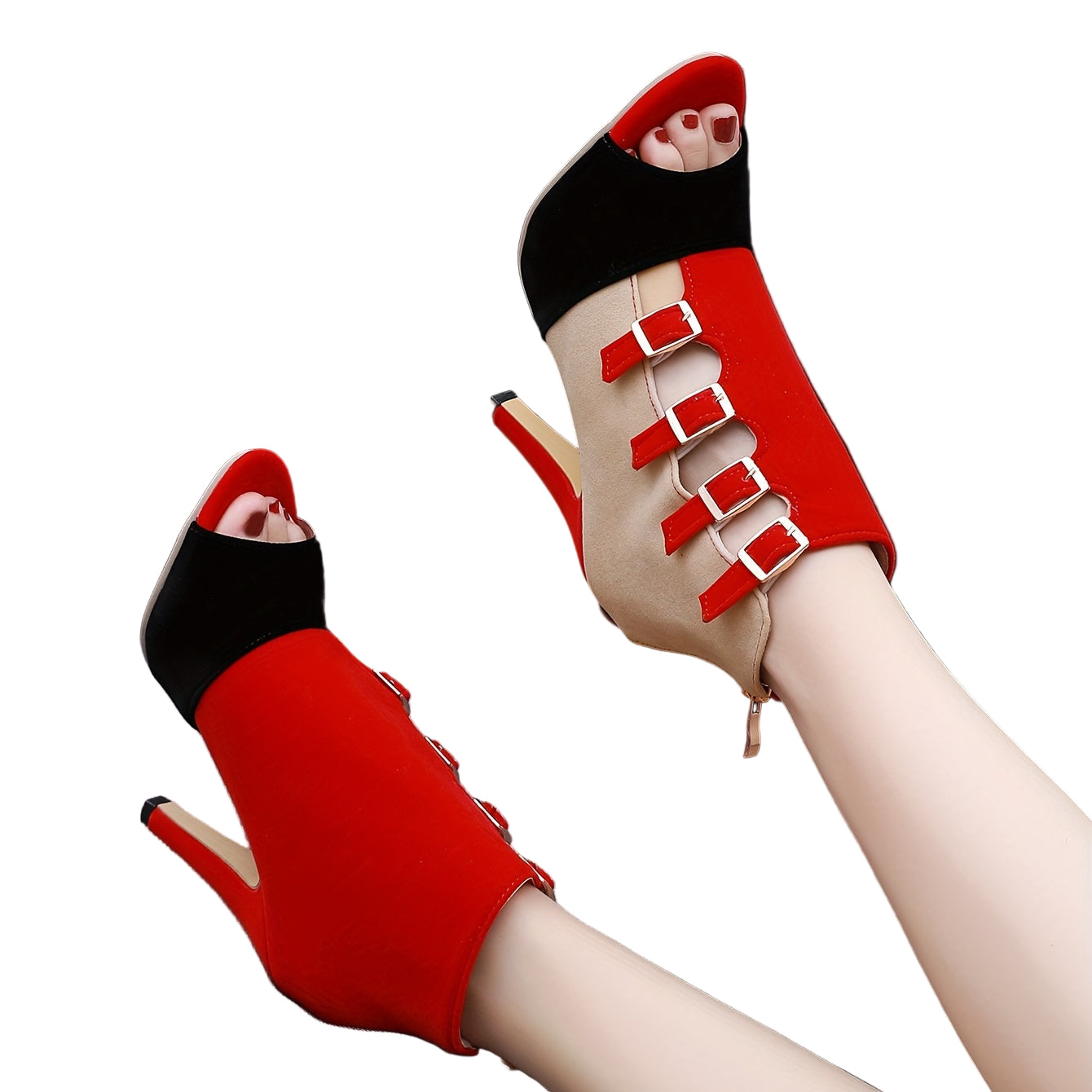 Red high-heeled shoes with buckles on a gray surface against a black background