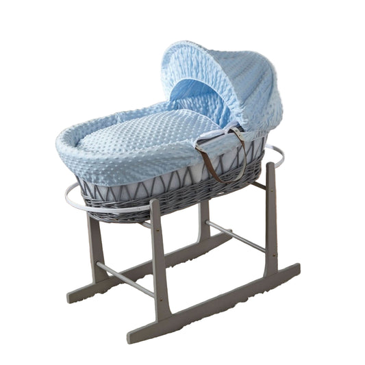 Baby Moses basket with blue and white pattern on a stand in a nursery setting.