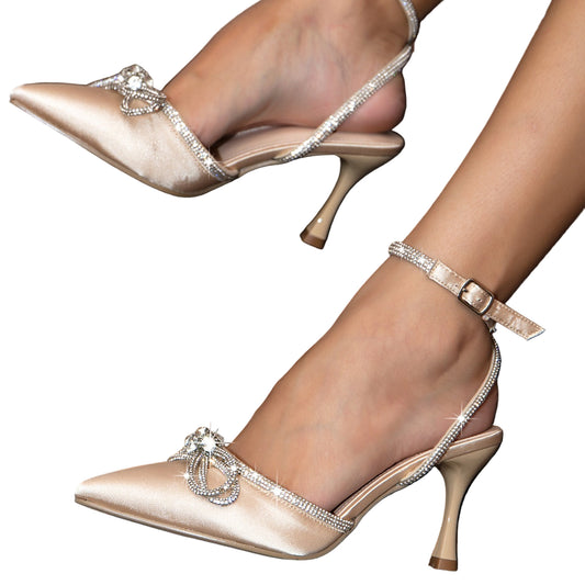 Beige high-heeled shoes with decorative straps on a patterned surface