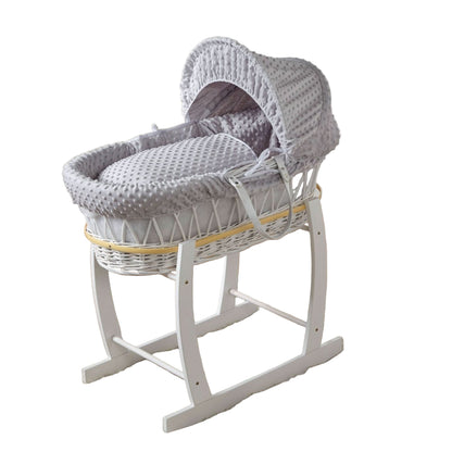 Gray wicker Moses basket with white stand on a wooden floor in a nursery setting.