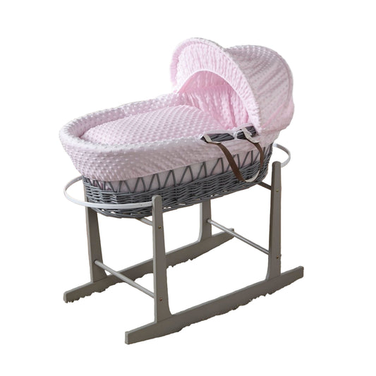 Pink wicker baby Moses basket on a stand in a nursery setting
